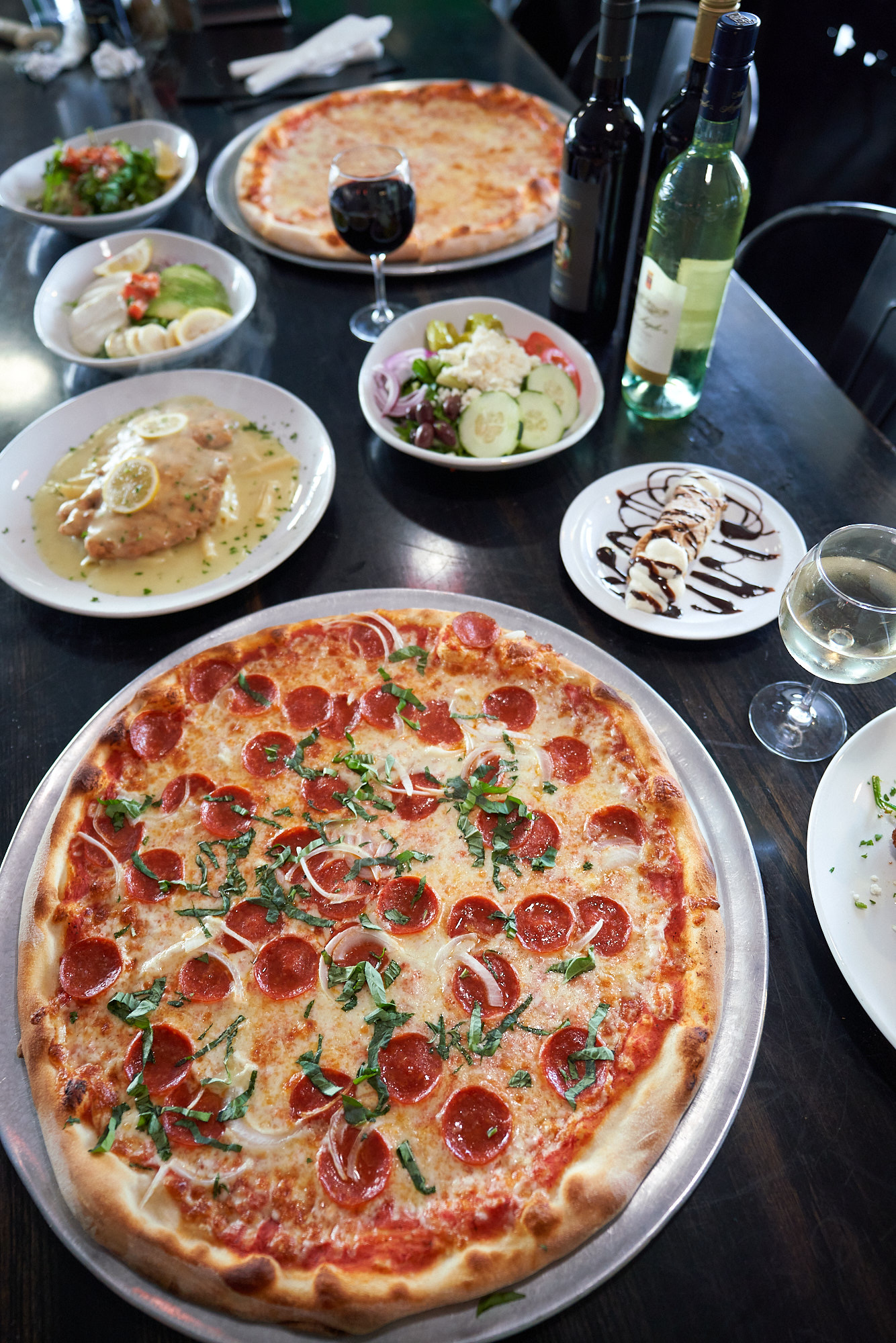 A spread of Rico's pizza, pasta, and wine